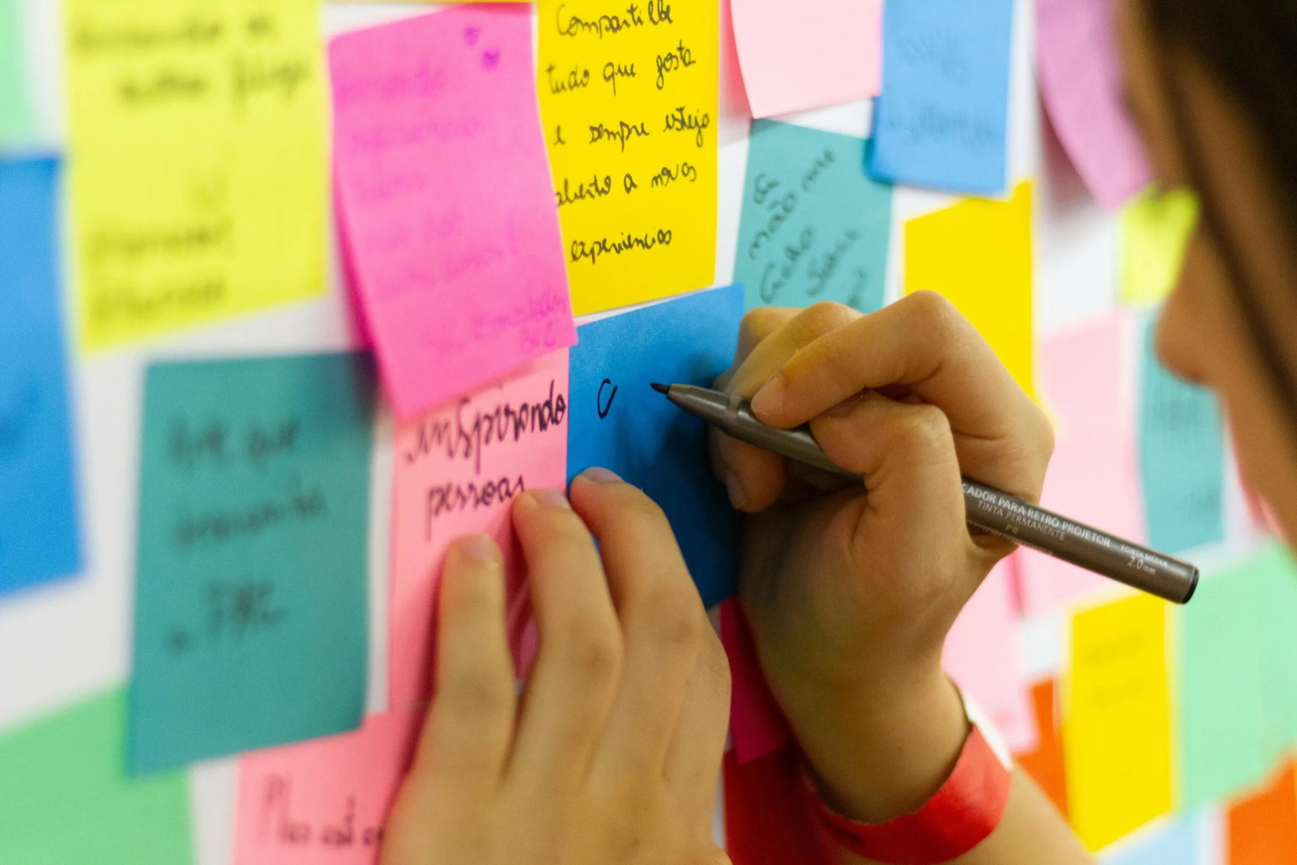 Person writing notes on sticky pads, reflecting brainstorming and analysis of attendee engagement metrics.