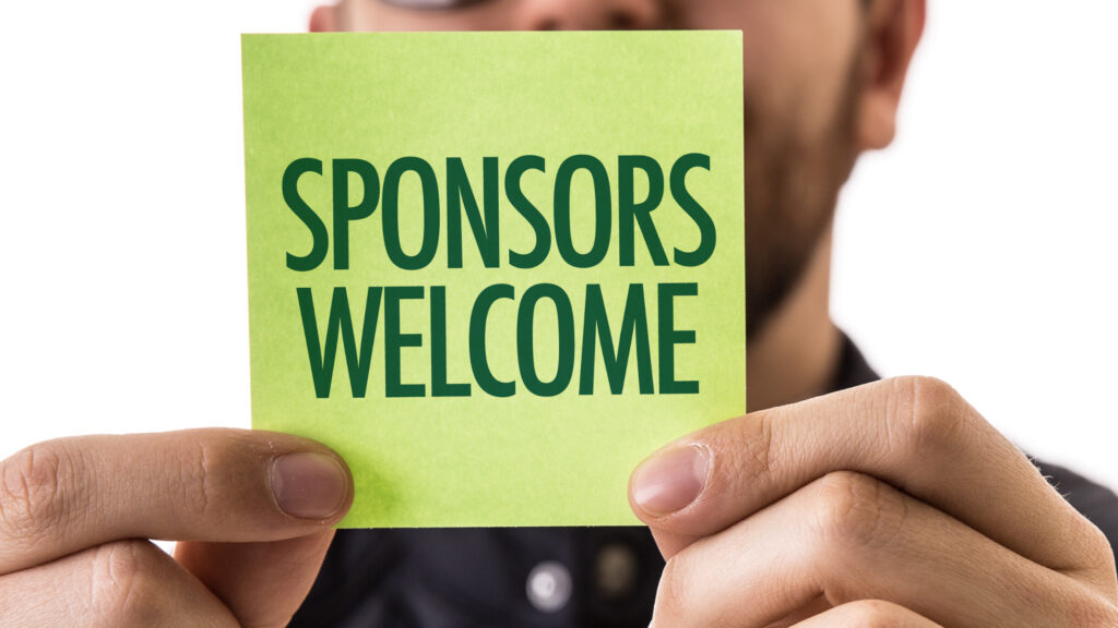 A sign on a post-it note held up by a corporate event executive saying sponsors welcome.