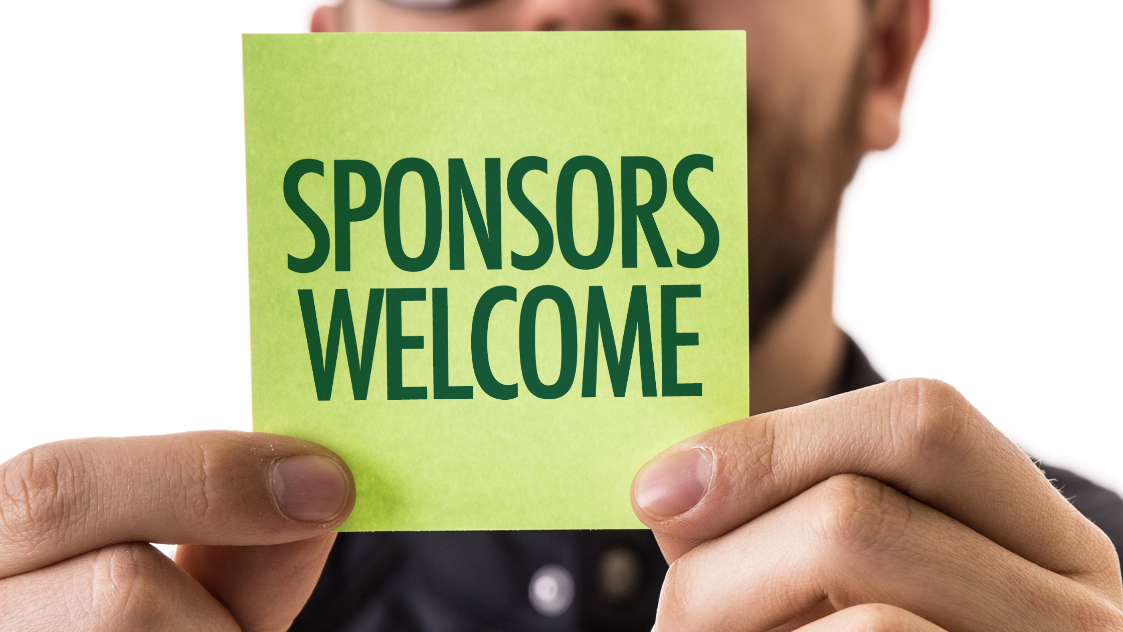 A sign on a post-it note held up by a corporate event executive saying sponsors welcome.