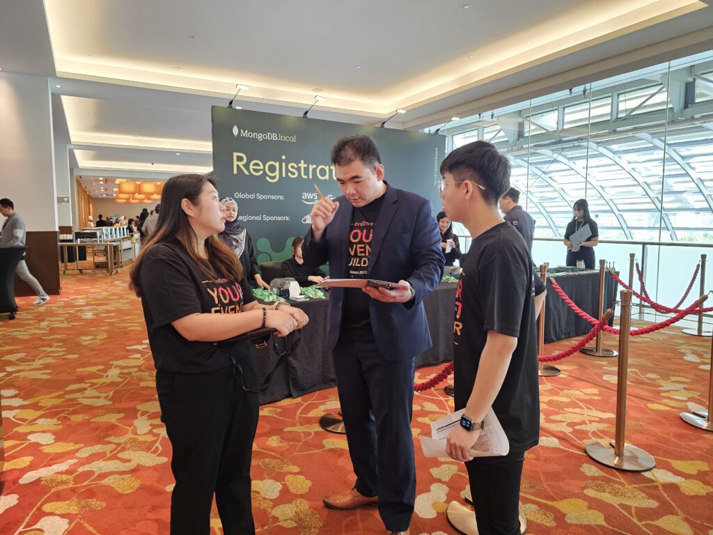 Three corporate event planning experts converse at an event registration area.