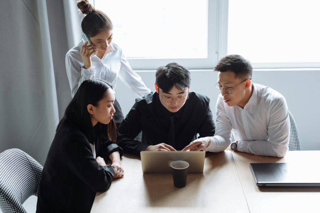A group of four networking event professionals engages in a focused discussion around a laptop.