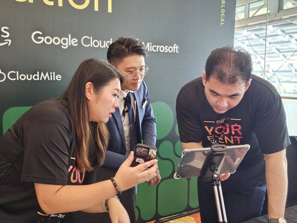 Three people in professional attire focus intently on an event registration system tablet at an event.